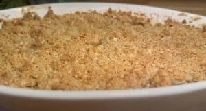 Golden apple crumble dessert in a white baking dish, with a crispy oat topping, ready to serve.